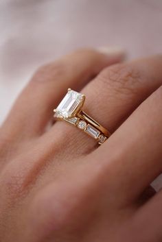 a woman's hand with a gold ring and two diamond rings on top of it