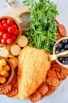 a platter filled with meat, veggies and crackers next to olives