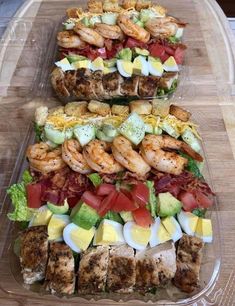 two trays filled with different types of food on top of a wooden cutting board