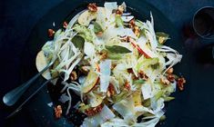 a salad with apples, cabbage and walnuts on a black plate