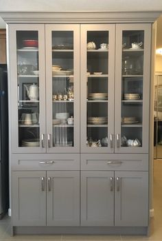 a large gray china cabinet with glass doors and shelves in the middle, filled with dishes