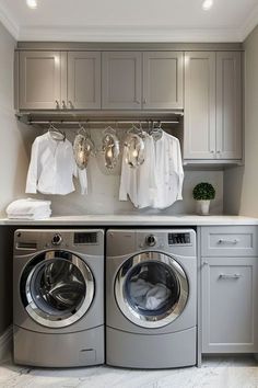 a washer and dryer in a laundry room with clothes hanging on the wall