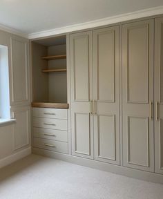 an empty room with white cabinets and drawers in it's center, next to a window