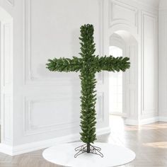 a cross made out of branches on top of a white table in an empty room