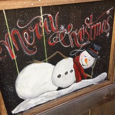 a painting of a snowman laying down on the ground next to a merry sign