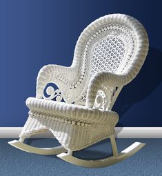 a white wicker rocking chair sitting on top of a hard wood floor next to a blue wall