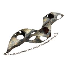 a metal mask with holes and chains hanging from it's sides on a white background