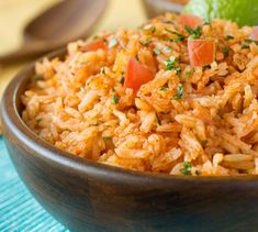 a bowl filled with rice and vegetables on top of a blue place mat next to a lime