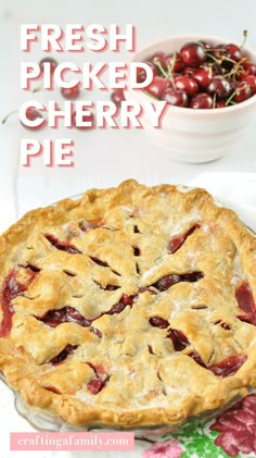 a cherry pie sitting on top of a table next to a bowl of cherries