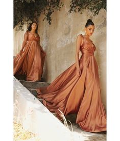 two women in long dresses standing next to each other on some steps and one woman is wearing an orange dress