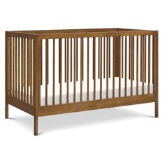 a wooden crib with white sheets on the bottom and side rails, in front of a