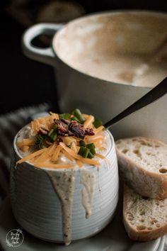 a white plate topped with bread and cheese next to a bowl filled with dip sauce