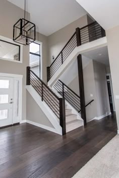 an empty living room with wood floors and stairs