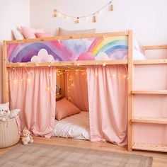 a child's bedroom with pink curtains and a rainbow mural on the wall above it