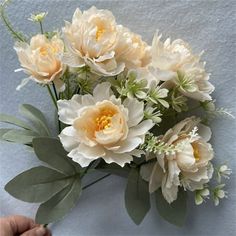 a bouquet of flowers is being held up by someone's hand on the wall