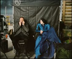 a man and woman sitting next to each other in front of a black backdrop,