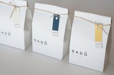 three bags with tags tied to them sitting next to each other on a white surface