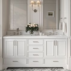 a white bathroom with two sinks and large mirrors on the wall next to each other