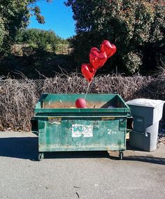 a green dumpster with red balloons in it