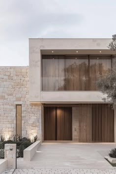 the front entrance to a modern house with large windows and wooden shutters on both sides