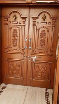 two wooden doors with ornate carvings on them in a room filled with tile flooring