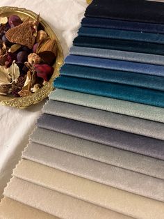 an assortment of different shades of fabric on a table with a gold plate next to it