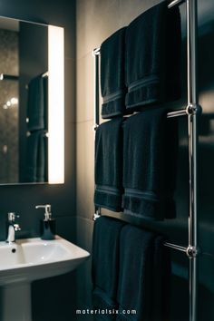 Black towels neatly hanging on a metallic towel rack in a modern bathroom.