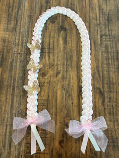 a pink and white beaded necklace with butterflies on the front, attached to a wooden table