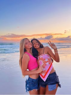 two beautiful young women standing next to each other on a beach