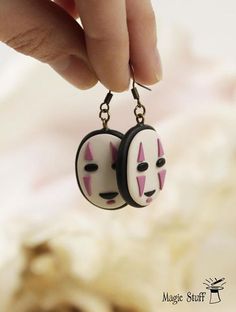 a pair of earrings with pink and black cat faces on them are being held by a person's hand