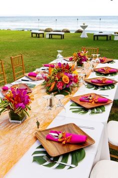 a long table is set up with plates and place settings for an outdoor dinner by the beach