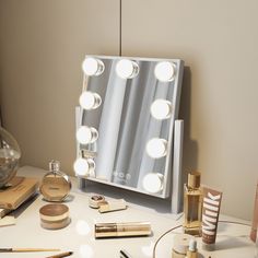 a vanity mirror with lights on top of it next to makeup brushes and other items