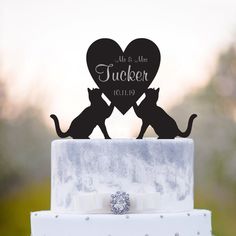 a wedding cake topper with two cats and a heart in the shape of a couple's initials