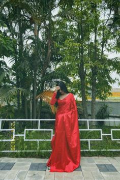 a woman in a red dress is holding an umbrella and looking out over the trees