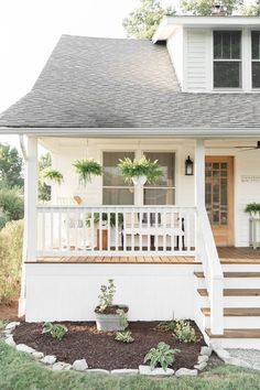 a white house with plants on the front porch