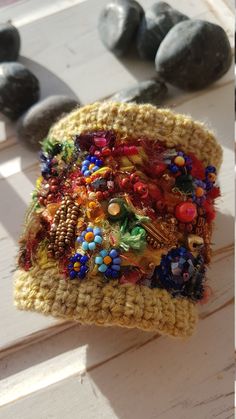 a crocheted purse with buttons and beads on it sitting next to some rocks