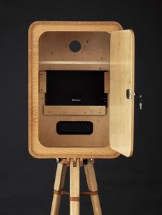 a wooden stand with a tv inside of it on top of a black wall background