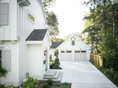 a white house with two garages and trees in the background