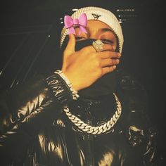 a person with a pink bow on their head covering her eyes while wearing a black jacket