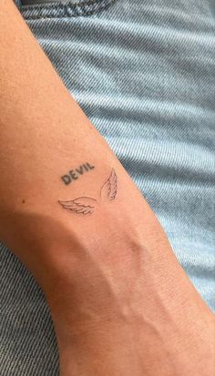 a man with a tattoo on his arm that reads devil and has an angel wing