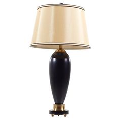 a black and gold lamp with a beige shade on the top, against a white background