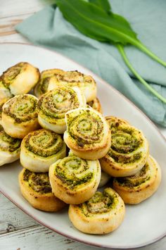 a white plate topped with rolls covered in pesto