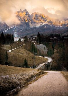 a scenic view of the mountains with a road going through it and a church in the distance