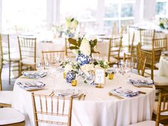 the tables are set with blue and white plates, silverware, and centerpieces