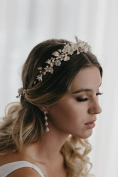 a woman wearing a bridal headpiece with flowers and pearls on her hair is looking off to the side