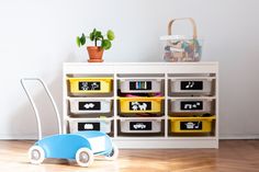 a toy car sitting in front of a white shelf filled with bins and books