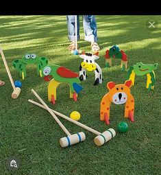 children playing in the grass with wooden toys and croquets on the ground