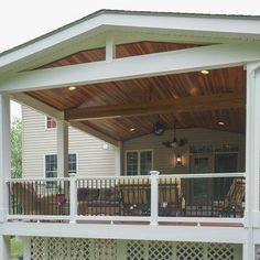 a covered patio with chairs and tables on the back deck, in front of a house