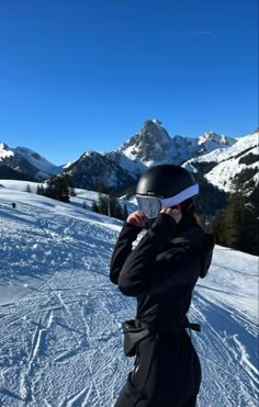 a person standing on top of a snow covered slope wearing skis and a helmet