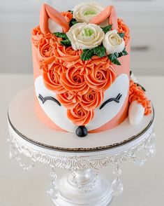 a cake decorated with flowers and an animal's face on top of a plate